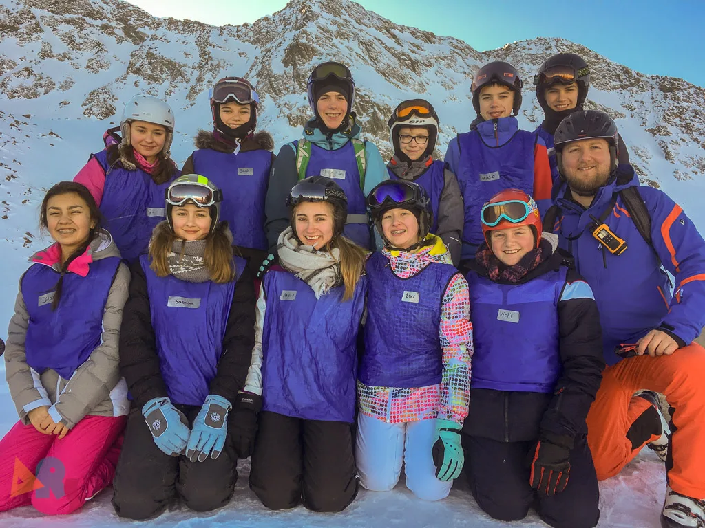 Skigruppe posiert vor der Bergkulisse im Abendlicht.